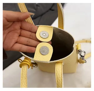 Gros plan du fermoir magnétique en métal sur un sac à bandoulière jaune motif litchi