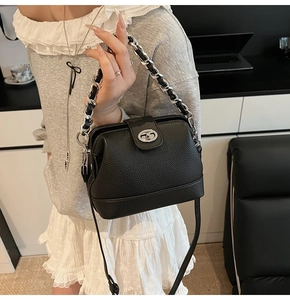 Detail view of black lychee-grain leather bucket bag with silver twist lock and chain handle