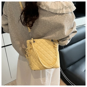 Détail du sac fourre-tout beige matelassé avec coutures fines et breloque étoile en cuir