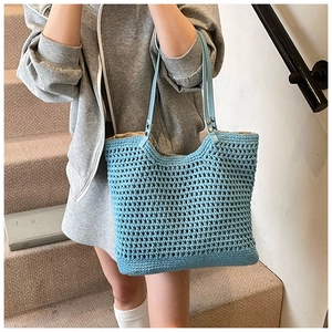 Detail of blue woven tote bag showing hollow knit pattern and leather shoulder strap