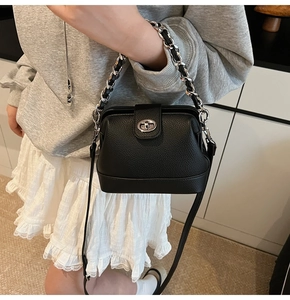 Close-up of black lychee grain leather handbag with silver rotating lock and chain strap