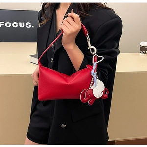 Dettaglio borsa hobo in pelle litchi rossa con charm elefante su modella in blazer
