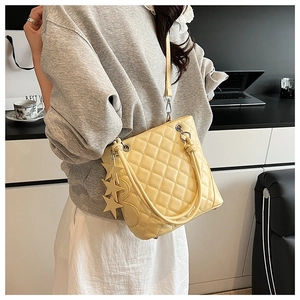 Détail d'un sac cabas crème matelassé avec breloques étoiles dans un décor de bureau