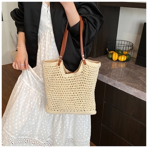Close-up of hand-woven tote bag showing hollow diamond mesh and brown leather handles