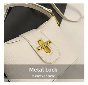 Detailed close-up of the elegant gold cross lock on a white lychee grain bucket bag