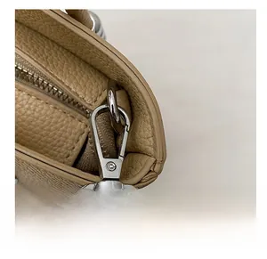Detailed macro view of silver metal hook and zipper on beige lychee leather bucket bag