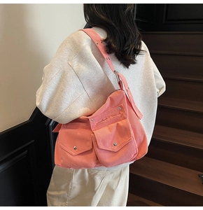 Détail du sac bandoulière en velours côtelé rose avec large sangle à œillets sur modèle