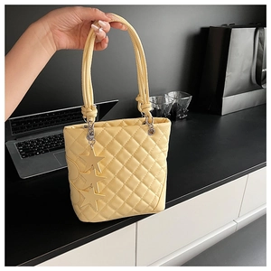 Détail d'un sac seau matelassé jaune avec pendentifs étoiles et poignée à nœud chic