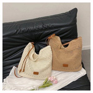 Detail of woven mesh tote bags in cream and khaki with leather straps on a sofa