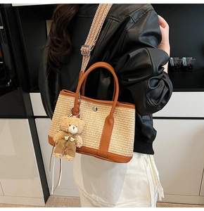 Détail du sac seau tissé avec bordure en cuir marron et bandoulière à motifs porté par le mannequin