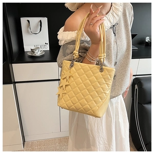 Gros plan sur le sac seau matelassé jaune vif avec breloques étoiles et texture losanges