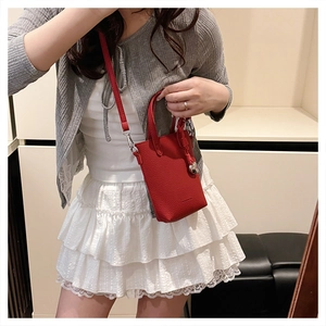 Détail du mini sac cabas rouge en cuir grainé avec un pendentif en cœur argenté
