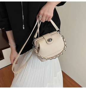 Close-up of beige lychee leather bucket bag with silver chain and twist lock detail