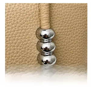 Detail showing pebbled leather texture and silver metal bead accents on the bucket bag