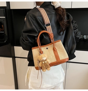 Détail du sac seau en paille tressée avec bordure en cuir marron et breloque ourson