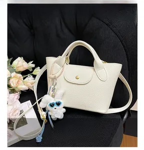 Detail of white lychee leather mini tote bag with gold buckle and cute rabbit charm