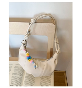 Detail of beige hobo bag with soft faux leather texture and colorful letter bead charm