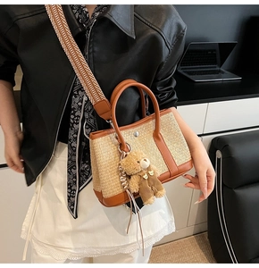 Détail du sac seau en paille tressée avec garniture en cuir brun et sangle en jacquard