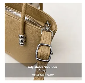 Close-up of adjustable strap with silver hardware on beige litchi leather bucket bag
