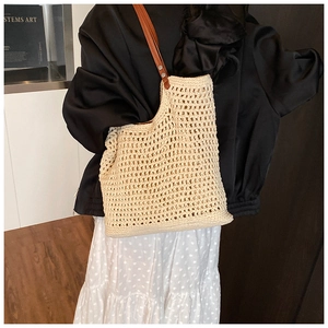 Detail of woven mesh tote bag featuring brown leather straps and metal rivet reinforcement
