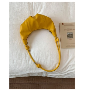 Detail of yellow croissant bag featuring soft pleats and decorative shoulder strap knots