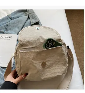 Detail der cremeweißen Nylon-Umhängetasche mit praktischer Fronttasche für Smartphones