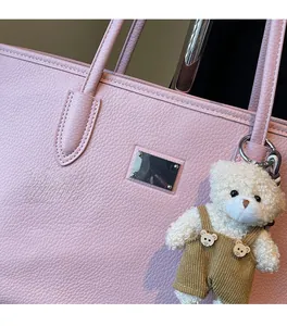 Detail of pink faux leather tote bag with lychee texture and cute bear pendant