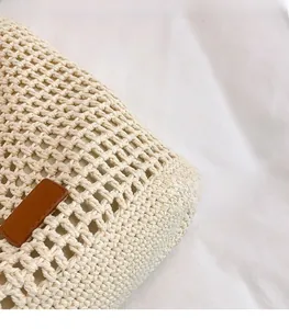 Detail of hand-woven cream tote bag showing mesh texture and brown leather label