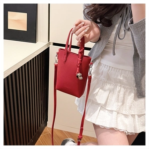 Détail d'un petit sac rouge avec pendentif coeur et fine bandoulière en cuir texturé