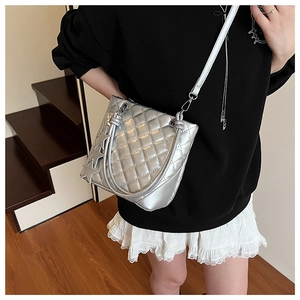 Détail du sac seau matelassé argenté avec charms étoiles porté par un mannequin chic