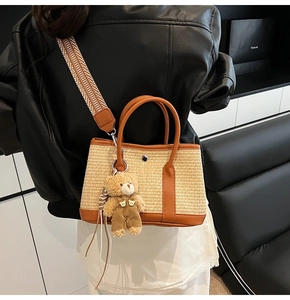 Détail du sac cabas en paille tressée avec bordure en cuir marron et pendentif ours