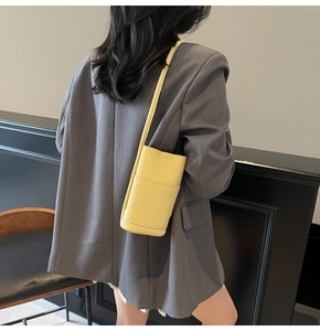Close-up of bright yellow litchi texture PU leather mobile phone crossbody bag worn by model