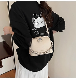 Detail of off-white lychee grain leather crossbody bag with silver chain and twist lock