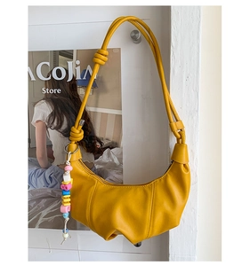 Detailed view of yellow dumpling bag with soft pleated faux leather and colorful bead charm