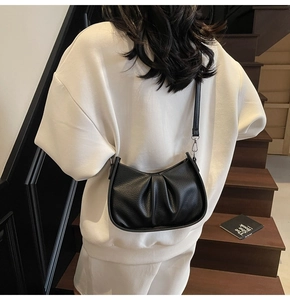 Detail of black pebbled leather cloud bag with silver hardware on a crossbody strap