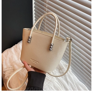 Close-up of beige lychee texture bucket bag with metal beads and leather embossing