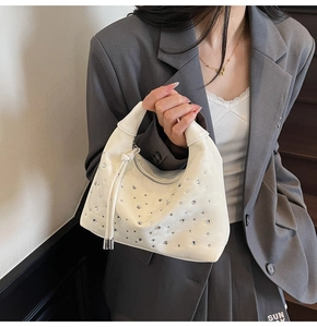 Detail of cream-white pleated handbag with hand-set rhinestones and a top zipper closure