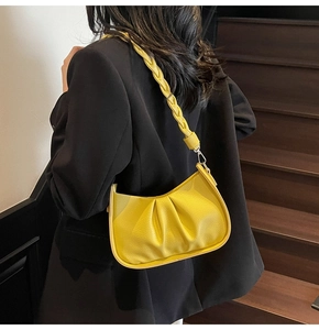 Detail of yellow crescent cloud bag with braided shoulder strap on black suit