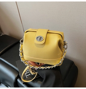 Detail of yellow lychee leather handbag with silver metal clasp and chain strap close-up