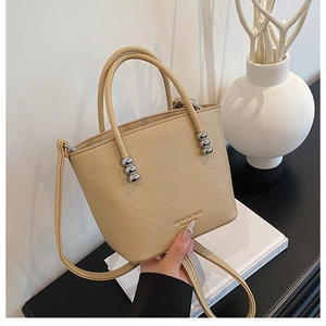 Detailed close-up of beige lychee grain leather bucket bag with silver bead handle decor