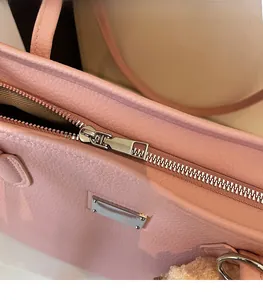 Macro detail of smooth silver metal zipper and lychee texture on pink leather tote bag
