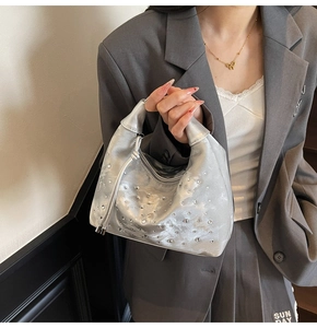 Detail of silver pleated hobo bag featuring dense rhinestone studs and a top handle