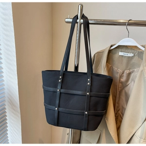 Detail of black tote bag featuring leather stripes and silver rivet decorations