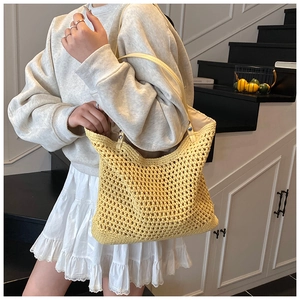 Detail of yellow woven tote bag featuring crochet texture and long faux leather straps