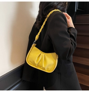 Detail of bright yellow ruched cloud bag with woven strap and pebbled leather texture