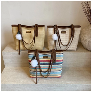 Detailed close-up of woven straw tote bags with leather handles and decorative charms