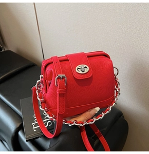 Detail of red lychee textured leather bucket bag with silver twist lock and chain strap