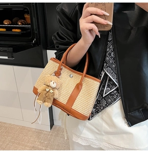 Détail du sac cabas en paille tressée avec anses en cuir marron et pendentif ourson