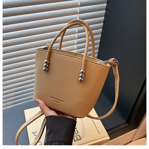 Detail of yellow lychee leather bag featuring silver bead accents and embossed logo