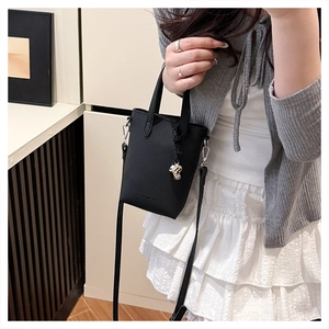 Détail d'un mini sac noir en cuir grainé avec breloque cœur et bandoulière amovible